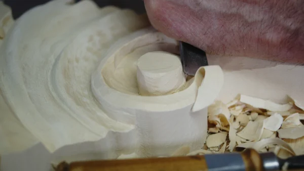 Hand-carving a scroll detail in solid wood